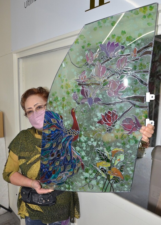 車の窓ガラスを活用したグラスアートを持つ今川美知代取締役。廃車の一部も、使い方によっては美しいインテリアに変わる