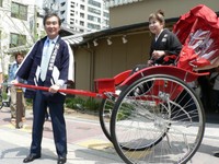 鈴木美智子さん（右）から贈呈された赤い人力車をひく桂三枝（現・桂文枝）＝2006年8月撮影