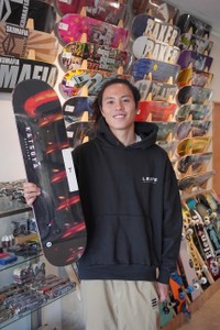 自らの名前が入った板を手にする中澤さん。韓国の大手スケボーメーカー「ティンバー」が中澤さんをプロライダーと認め製造した（亀岡市北町・ＬＥＡＰＳ）