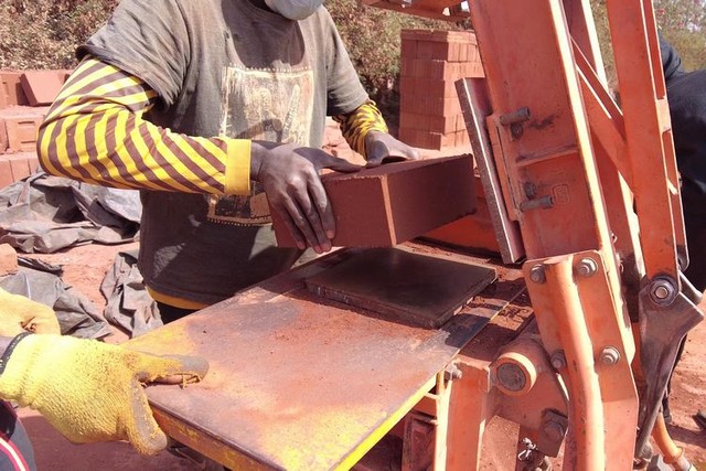 人力の圧縮機械を使い、土れんがをつくる「エレメンテール」の作業員ら＝2023年12月23日、セネガル西部、荒ちひろ撮影