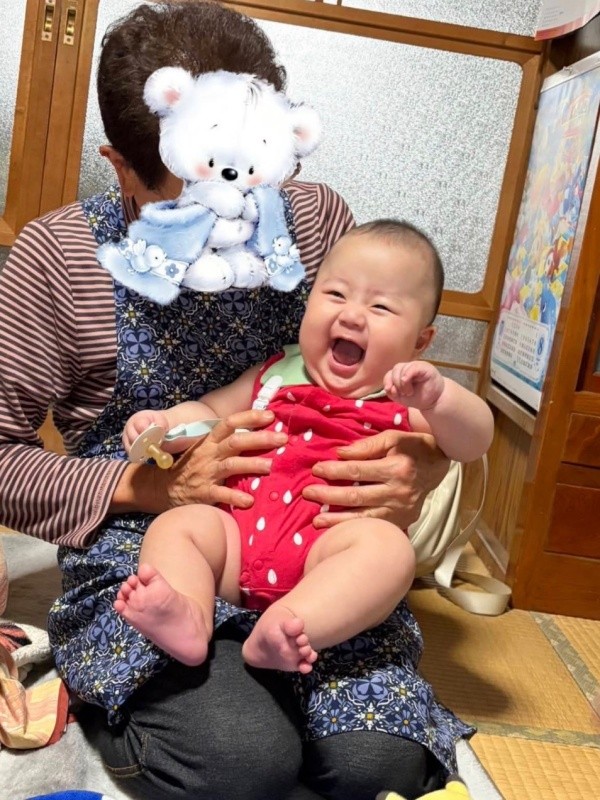 おばあちゃんに抱っこされて、にこにこ笑顔の息子さん（画像提供：まちっさん）