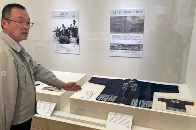 朝ドラ「ばけばけ」の衣装の参考となった牛乳店の法被を紹介する新庄正典主任学芸員＝島根県松江市、松江歴史館
