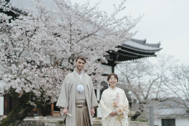 和装姿で笑顔を見せる2人。背景には京都の寺院と満開の桜／投稿主さん提供