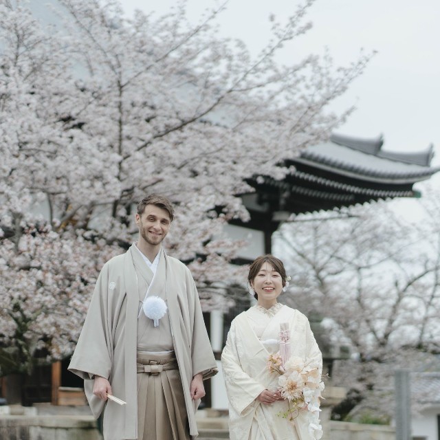 和装姿で笑顔を見せる2人。背景には京都の寺院と満開の桜／投稿主さん提供
