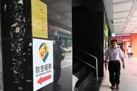 台北市の商業ビル１階に貼られた、地下防空壕の位置を示す新旧の標識。上の黄色いものが旧版で、収容可能人数が記されている＝石田耕一郎