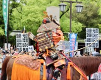 5月25日に神戸市内で行われた楠公武者行列で、自身を批判するプラカードが上がる沿道に向かって手を振る兵庫県の斎藤元彦知事