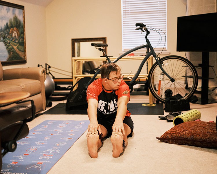 Chris Nikic stretches in the training room at his home in Maitland, Fla., Nov. 14, 2020. Nikic, 21, became the first person with Down syndrome to conquer the grueling Ironman endurance race, offering lessons in perseverance and hope. (Zack Wittman/The New York Times)