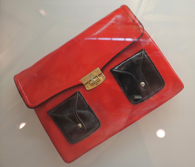 『カーネーション』の直子（川崎亜沙美）と優子（新山千春）が奪い合った赤いバッグ。糸子（尾野真千子）が「お化け」と称する奇抜なファッションに身を包んだ直子が岸和田に帰郷した際に持っていたクラッチバッグ仕様（肩紐がない）