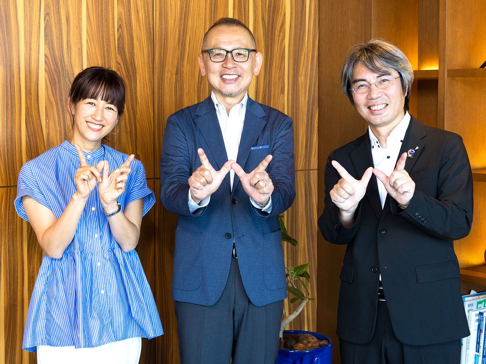 「Well-Crossing」ポーズを指でつくる、相鉄アーバンクリエイツ横浜駅西口事業部長の福﨑努さん（写真右）、前野隆司武蔵野大学教授（同中央）、フローリストの前田有紀さん（同左）