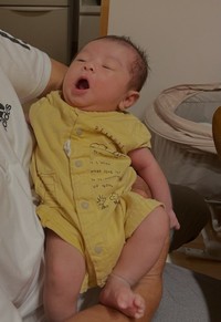 1枚目。義父に抱っこされ、あくびをする赤ちゃん（まるさん提供）
