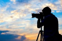 夕日の中で写真を撮る写真家のシルエット※画像はイメージです （Tijana/stock.adobe.com）