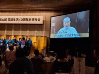 玉袋筋太郎の「芸能生活40周年を祝う会」で大画面からメッセージを贈る毒蝮三太夫を見守る会場の様子＝東京・明治記念館