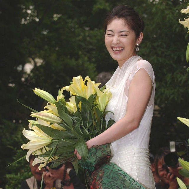 ユリの花を手に笑みを浮かべる常盤貴子＝2004年