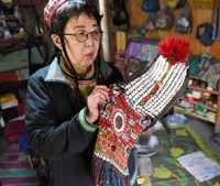カラーシャの谷の女性たちが儀式などの際に使う頭飾りを持つ和田晶子さん＝2019年4月17日、パキスタン北西部、乗京真知撮影
