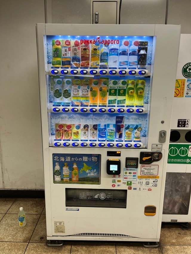 取り出し口に、買った覚えのない不審なペットボトル飲料があったという自動販売機。自販機の左横下に写っているのが「不審なペットボトル飲料」（画像提供：速度さん）