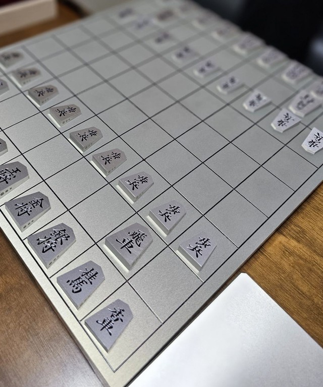 上品な光沢と硬質な形状にこだわったアルミ製の将棋盤と駒。手前はアルミ製の駒台の一部
