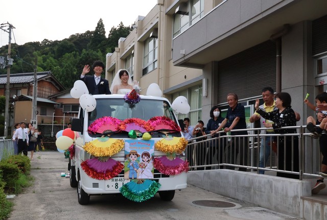 軽トラックの「オープンカー」に乗る２人を祝福する住民たち（宮津市小田）