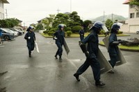 警備実習で盾を持って走る記者（左端）。徐々に隊列から遅れていく