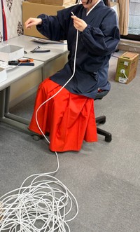 床にとぐろを巻くケーブルを引き出す巫女／穴守稲荷のコンちゃん【公式】（@KK14_kon_chan）提供