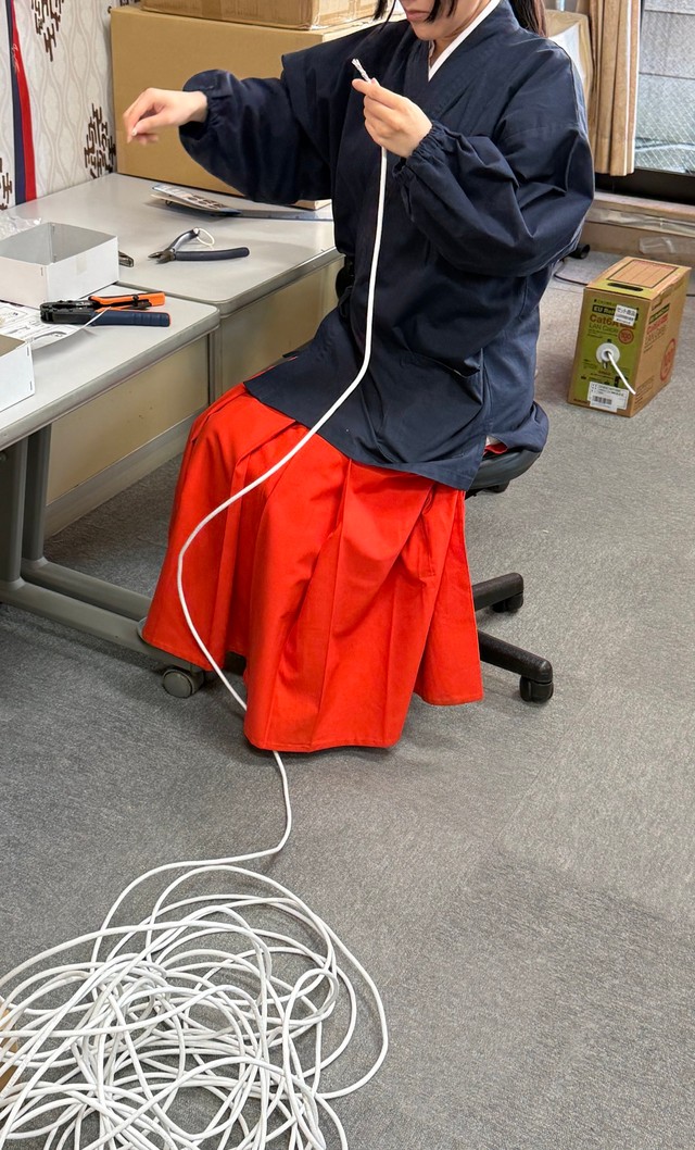 床にとぐろを巻くケーブルを引き出す巫女／穴守稲荷のコンちゃん【公式】（@KK14_kon_chan）提供