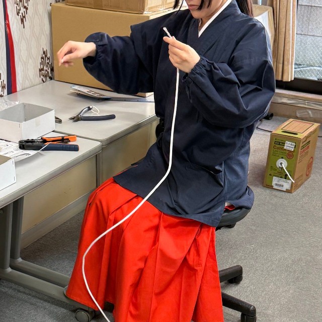 床にとぐろを巻くケーブルを引き出す巫女／穴守稲荷のコンちゃん【公式】（@KK14_kon_chan）提供