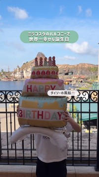 ミラコスタのバルコニーで「HAPPY BIRTHDAY」の風船を手に微笑む息子さん。背景には朝のディズニーシーの風景が広がる／ゆっきーさん（@yuki.m.h）提供