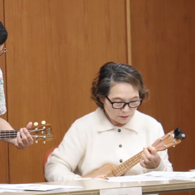 講師の水谷さん（中央）にウクレレの手ほどきを受ける参加者＝南丹市八木町・八木市民センター
