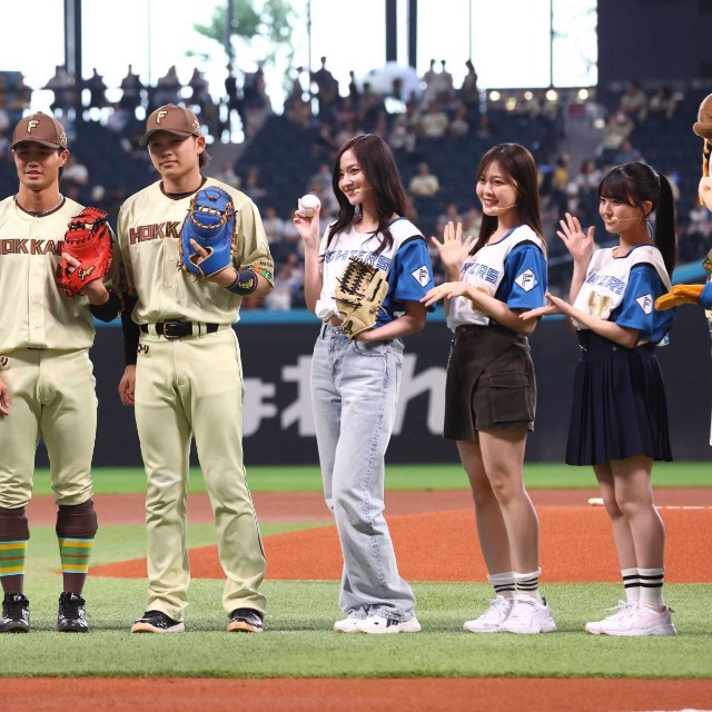 試合前、ファーストピッチセレモニーに登場し、記念撮影に応じる乃木坂野球部と日本ハム・細川凌平（左）、日本ハム・田宮裕涼＝エスコンフィールド北海道