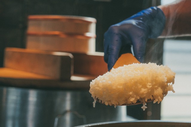 米屋がつくるおむすび屋「十字屋商店」では、真庭産の循環するお米（めぐりまい）を羽釜で炊いたおむすびや定食を。水車で24時間かけて行う精米は、精米時の熱を帯びないためふっくら柔らかく甘みのあるお米に炊き上がる（真庭あぐりガーデン提供）