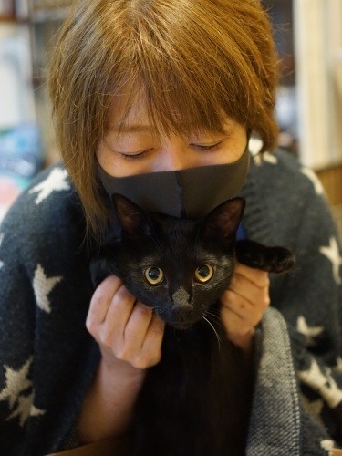 ヤソ次郎を抱くのりかさん。動物看護師として猫の病院シュシュで働き、アサジの最晩年をみた。その後もシロミさんのケアを続けた。「私も一人暮らしで飼った最初の猫が黒猫。“１対１”の関係を失うつらさがよくわかったし、黒猫の後はやっぱり黒猫が飼いたくなるんですよね……」今は自宅で３匹の黒猫と暮らす。シロミさんの最強の黒猫友