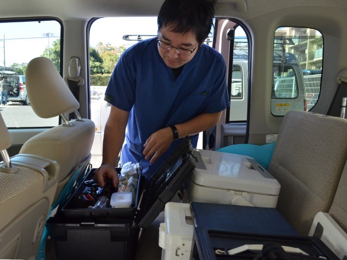 往診用の車の中に置いてある器具をチェックする桜井院長