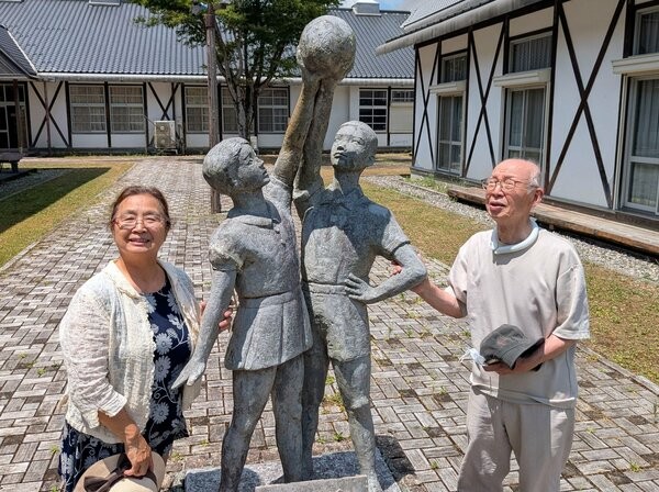 木代さん（右）が旧鶴ケ岡小での在職中に制作し、今も立っている男女像「感動」。教え子の小畑さん（左）がモデルを務めた（京都府南丹市美山町）