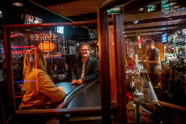 David Meinert, center, owner of 5 Point Cafe, one of the city's oldest, chats with a friend at the bar, in Seattle, Nov. 7, 2020. Meinert had a cozy, heated outdoor area constructed for his patrons, upgraded the heating, venting and air conditioning system's filters, and installed virus-inhibiting UV-C lights on the ceiling, just to name a few of the safety measures he's taken — which might surprise some given the bar's slogan: Alcoholics serving alcoholics since 1929. (Stuart Iset/The New York Times)