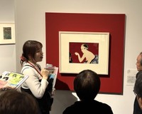 学芸員の説明に聞き入る来場者たち。新版画の奥行きが静かに広がる＝神戸ファッション美術館