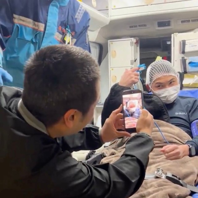 救急隊員の制止を聞かず、救急車内でポーズを取る傷病者を記念撮影する友人……の様子を志摩市消防本部の職員さんたちが再現。こういった「救急現場」での非常識な撮影行為が横行しているという（動画からキャプチャー／提供：志摩市消防本部【公式】）