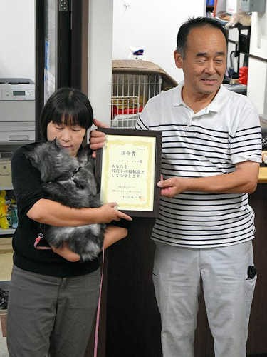 駅長の辞令をしょこらの飼い主の細谷絵里子さん（左）に渡す江本一男さん