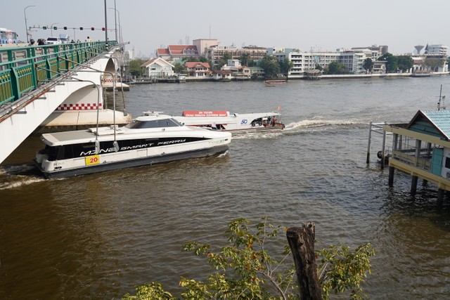 チャオプラヤ川を行き交う電動フェリー（手前）とディーゼルエンジンのフェリー（奥）