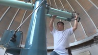 望遠鏡を慣れた手つきで操作する松野俊博さん