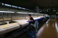 幅２４メートルの織機を使い、手作業で作品を織る職人たち。下絵を元に横糸を通していく（京都市左京区）