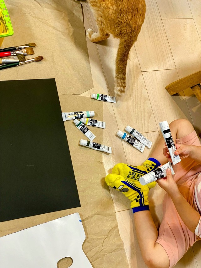 床に広げた絵の具の中から、使う色を選ぶ（添田一平さん提供）