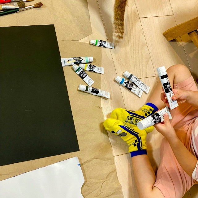 床に広げた絵の具の中から、使う色を選ぶ（添田一平さん提供）