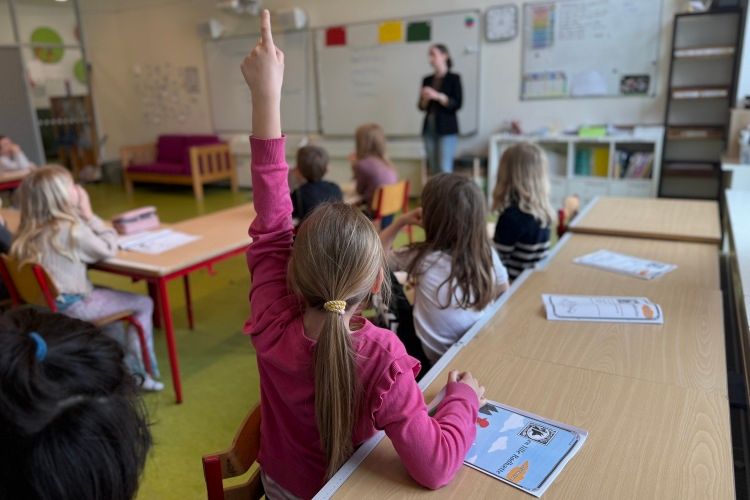 国語の「赤ずきんちゃん」の授業で手を挙げる小学1年生