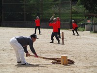 「第1回 全日本棍棒飛ばし選手権大会」団体戦　攻撃側（手前）が棍棒を打ち飛ばし、それを守備側は打ち返して妨害する＝大宇陀健民グラウンド（奈良県宇陀市内）