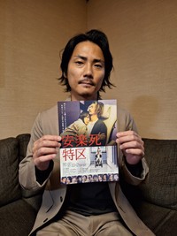 2026年1月公開の主演映画「安楽死特区」のチラシを手にする俳優の毎熊克哉＝都内