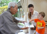 富坂さん（左）から本の寄贈を受けるフリブちゃんと母親のアンナ・シェルシュノヴァさん＝京都市左京区・市国際交流会館
