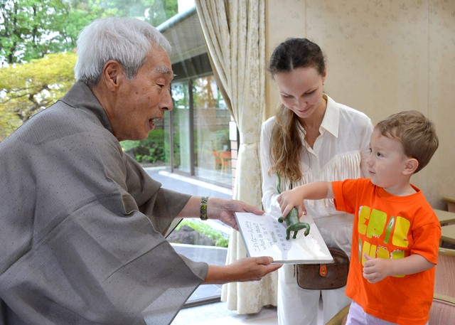 富坂さん（左）から本の寄贈を受けるフリブちゃんと母親のアンナ・シェルシュノヴァさん＝京都市左京区・市国際交流会館
