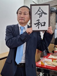 菅義偉元首相のそっくり芸人「ドラQ」。会場の至る所に登場した＝東京・浅草の「漫画ギャラリーCAFEオカオカ」