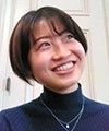 読者の伊奈東子さんの顔写真。紺色の服でショートヘア。笑いながら顔を上げている