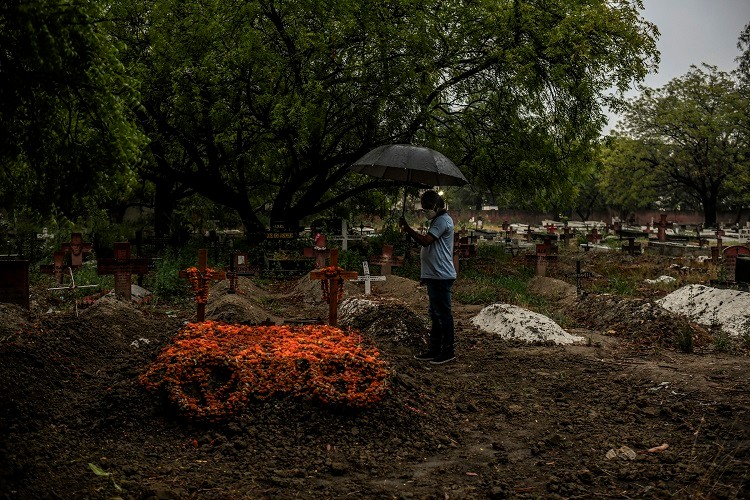 A mourner visits the graves of Joefred and Ralfred Gregory in Meerut, India, May 19, 2021. The touching story of the twins who lived and died together has spread fast and wide on Indian social media, puncturing this nation's numbing statistics — the daily COVID-19 case numbers, the death counts, the infection rates. (Atul Loke/The New York Times)