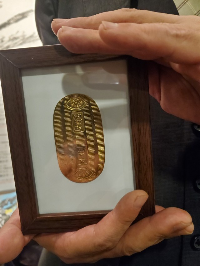 ３０年以上前に藤田まことさんから山田誠二氏に贈られた「小判」。小道具だが〝家宝〟として額装している